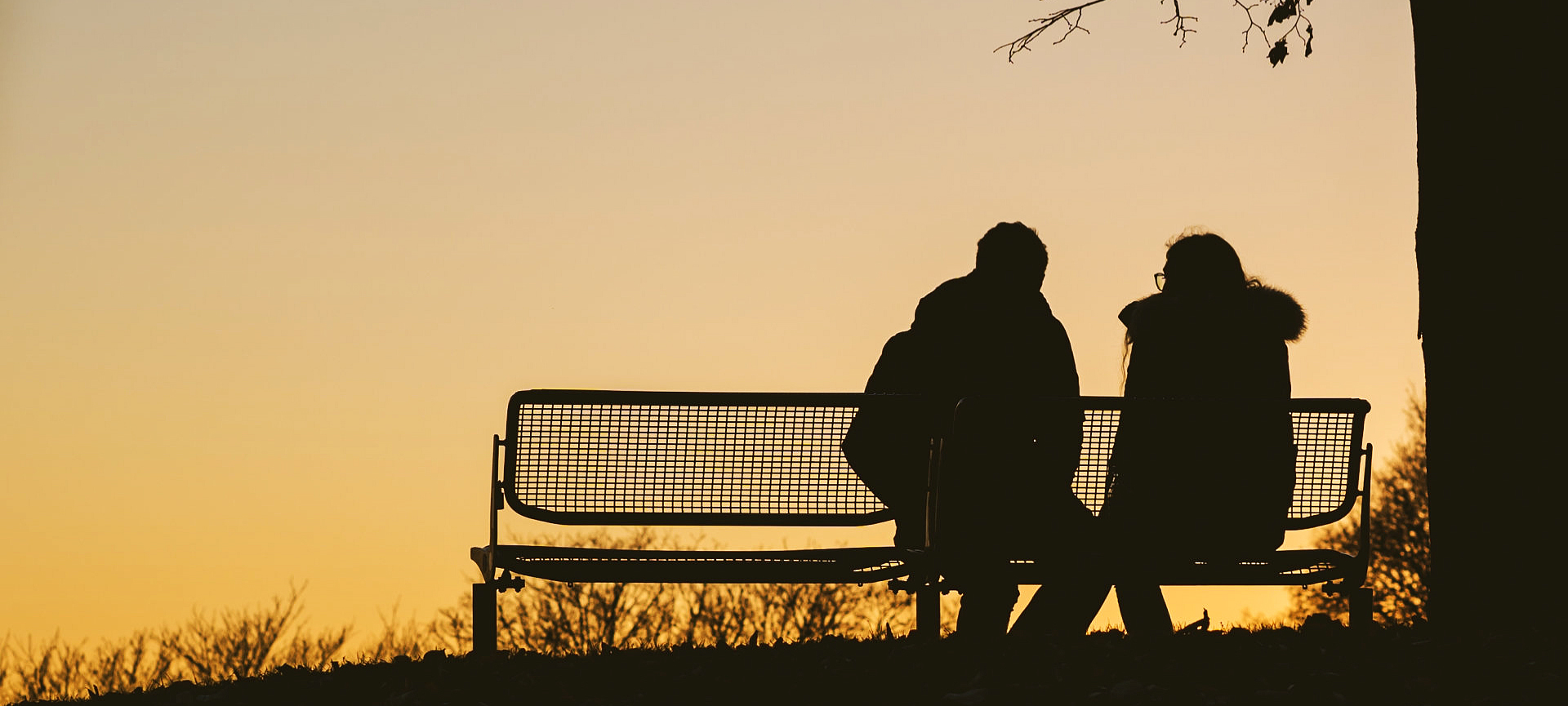 silhouette of couple sitting on bench